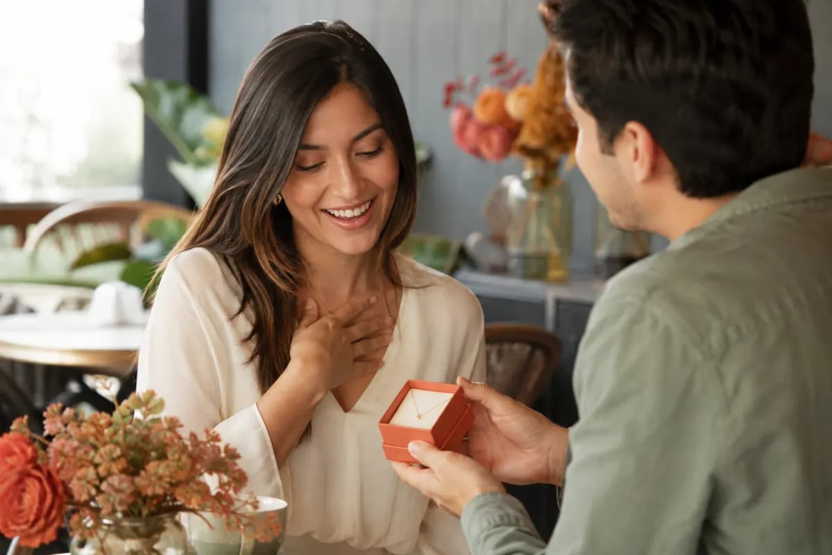 Mujer recibiendo de su pareja una caja con un collar delicado